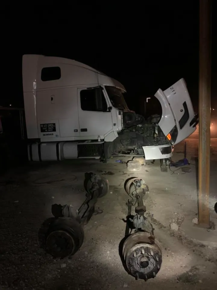 A white truck with its front end and the hood open